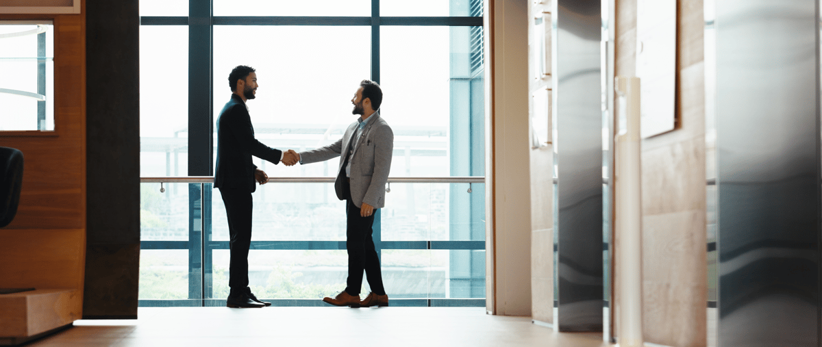 Business men shaking hands by a window email header image