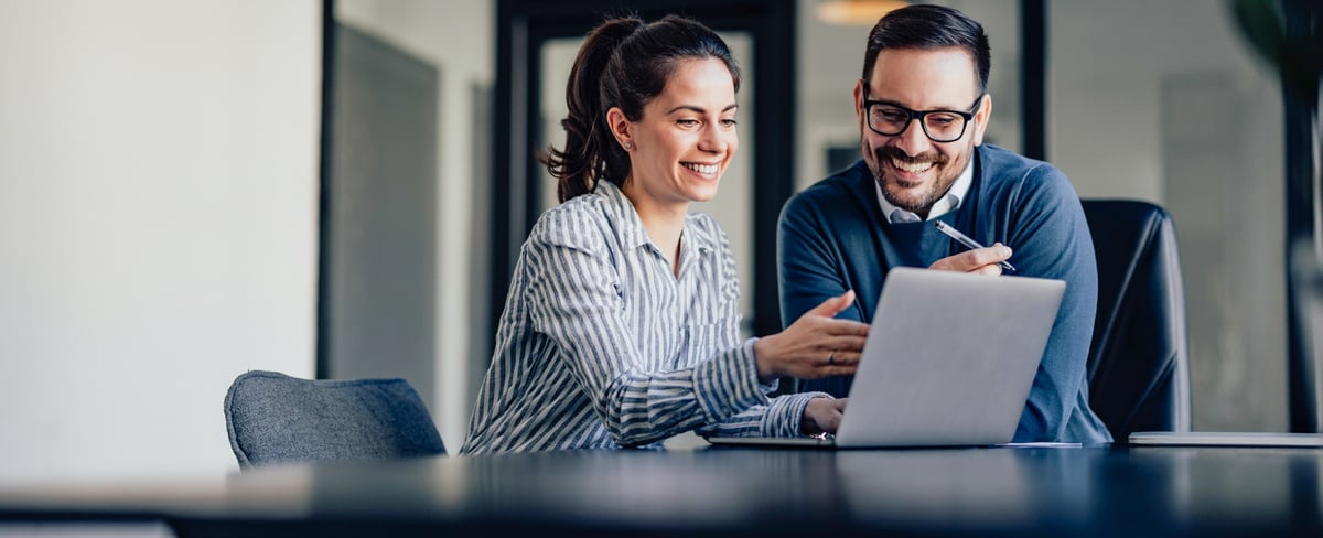 Man and woman in blue smiling at laptop email header image